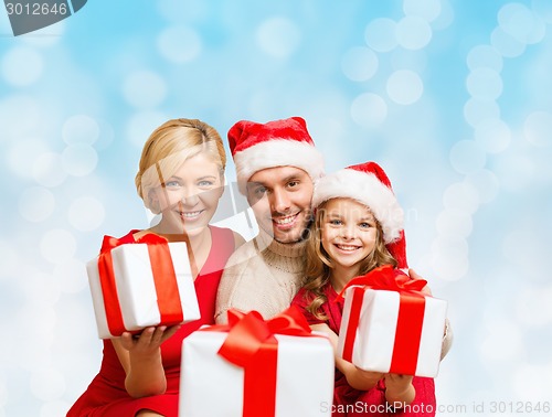 Image of happy family in santa helper hats with gift boxes