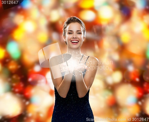 Image of laughing woman in evening dress holding something