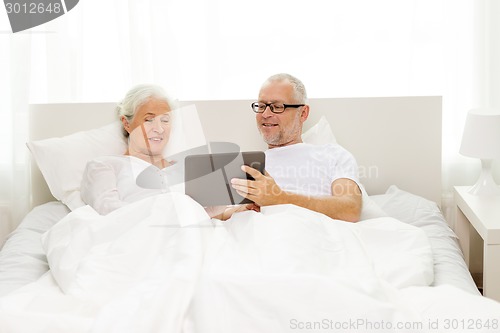 Image of happy senior couple with tablet pc at home