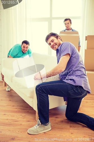 Image of smiling friends with sofa and boxes at new home