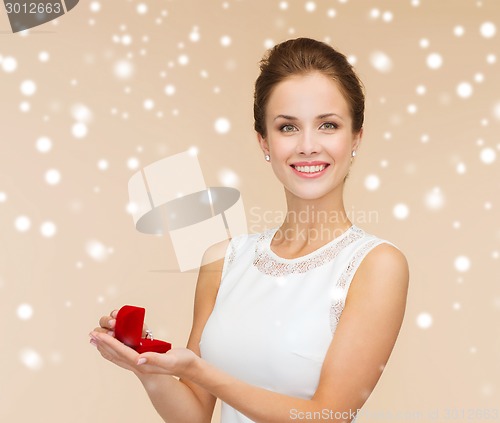 Image of smiling woman holding red gift box with ring