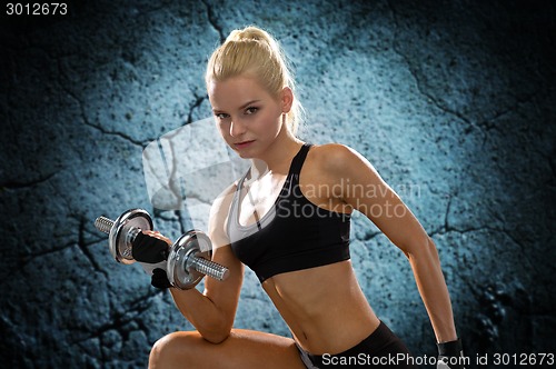 Image of young sporty woman with heavy steel dumbbell