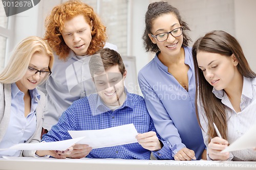 Image of smiling team with paper at office