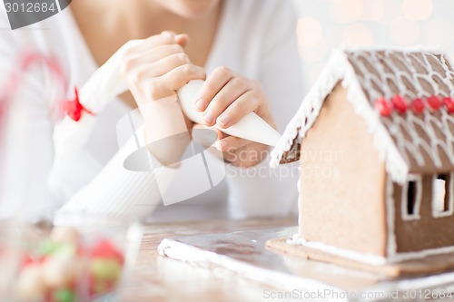 Image of close up of woman making gingerbread house at home