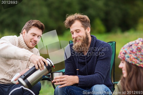 Image of group of smiling tourists cooking food in camping