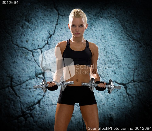 Image of young sporty woman with dumbbells flexing biceps