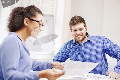 Image of smiling team with paper at office