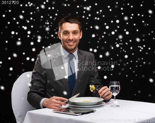 Image of smiling man with tablet pc eating main course