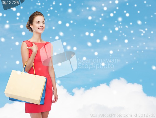 Image of smiling elegant woman in dress with shopping bags