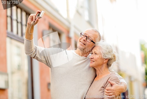 Image of senior couple photographing on city street