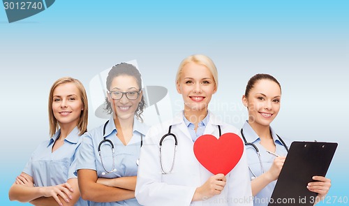 Image of smiling female doctor and nurses with red heart