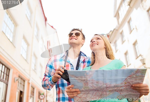 Image of smiling couple with map and photo camera in city