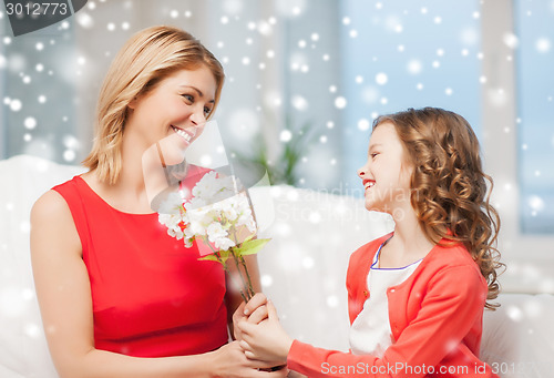 Image of smiling mother and daughter with flowers at home