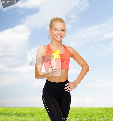 Image of smiling sporty woman with protein shake bottle