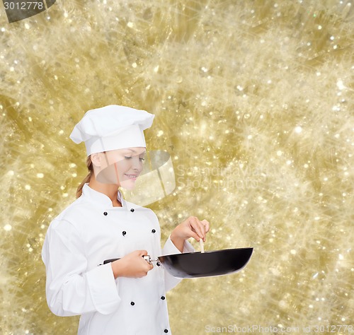 Image of smiling female chef with pan and spoon