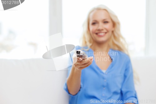 Image of smiling teenage girl with tv remote control