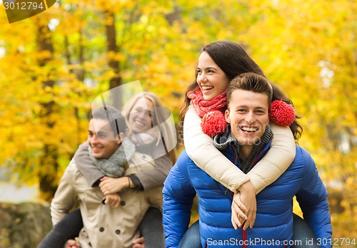 Image of smiling friends having fun in autumn park