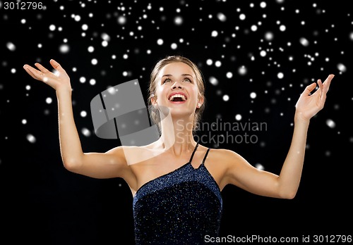 Image of smiling woman raising hands and looking up