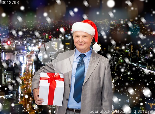 Image of smiling man in suit and santa helper hat with gift