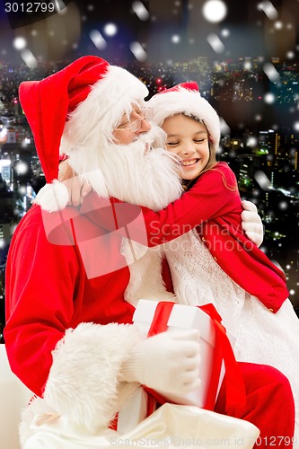 Image of smiling little girl with santa claus and gifts