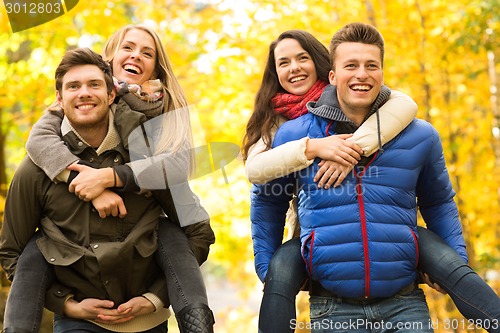 Image of smiling friends having fun in autumn park