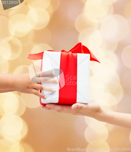 Image of close up of child and mother hands with gift box