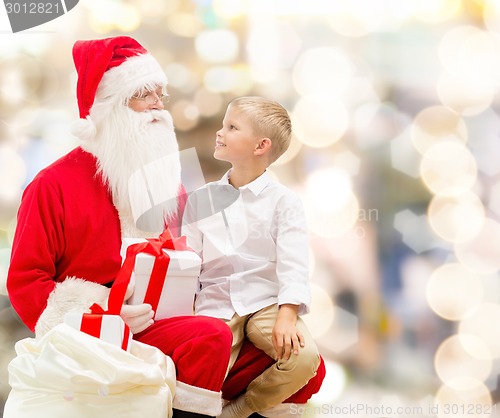 Image of smiling little boy with santa claus and gifts