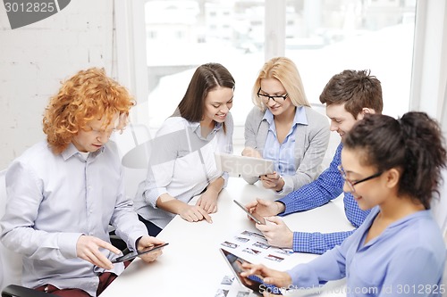 Image of smiling team with table pc and papers working