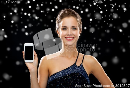 Image of smiling woman in evening dress holding smartphone