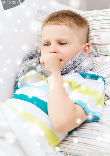 Image of ill boy with scarf lying in bed and coughing