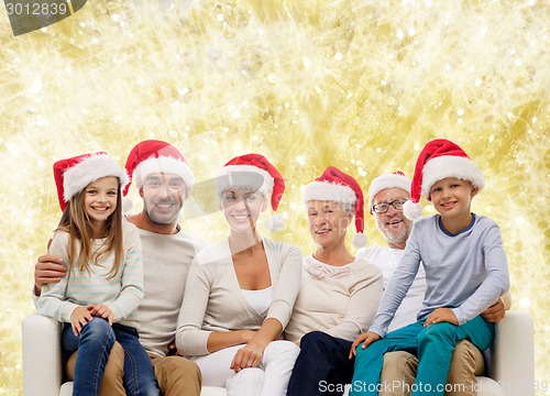 Image of happy family in santa helper hats sitting on couch