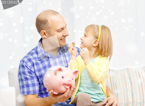 Image of happy father and daughter with big piggy bank