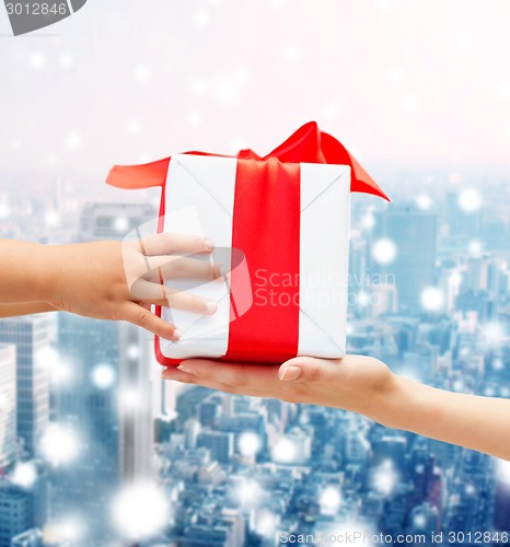 Image of close up of child and mother hands with gift box