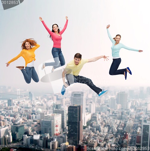 Image of group of smiling teenagers jumping in air