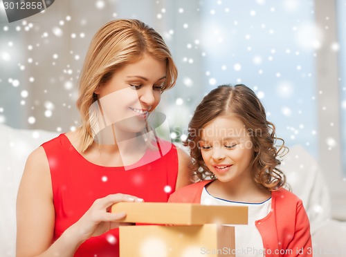 Image of smiling mother and daughter with gift box at home