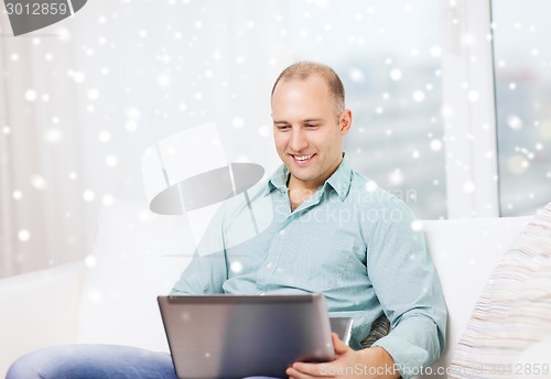 Image of smiling man working with laptop at home