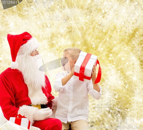 Image of smiling little boy with santa claus and gifts