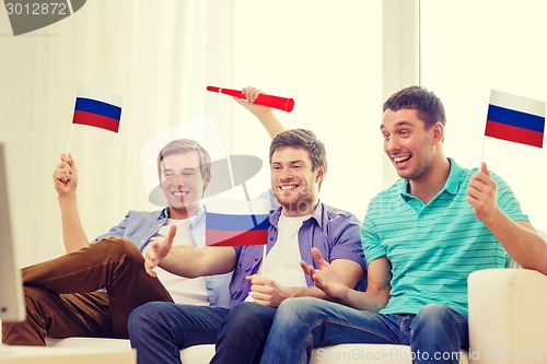 Image of happy male friends with flags and vuvuzela