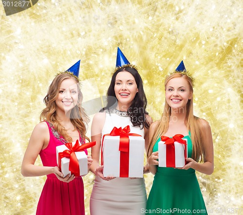 Image of smiling women in party caps with gift boxes