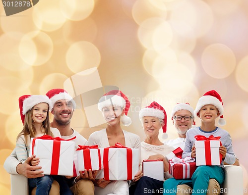 Image of happy family in santa helper hats with gift boxes