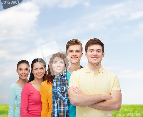 Image of group of smiling teenagers over blue sky and grass