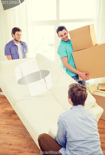 Image of smiling friends with sofa and boxes at new home