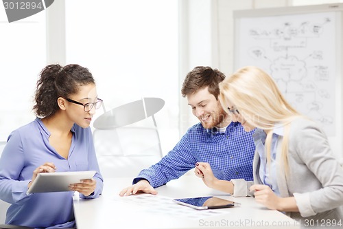 Image of smiling team with table pc and papers working