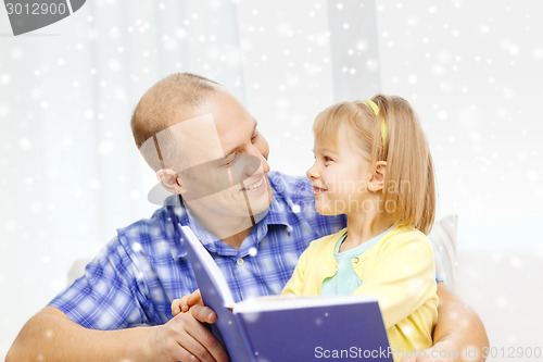 Image of smiling father and daughter with book at home