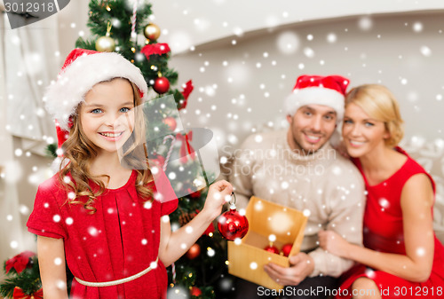 Image of smiling family decorating christmas tree at home