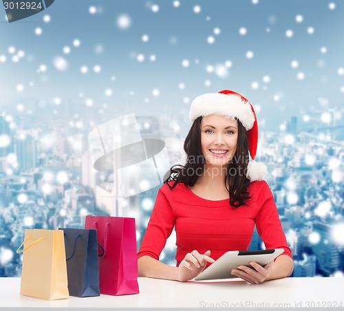 Image of smiling woman with shopping bags and tablet pc