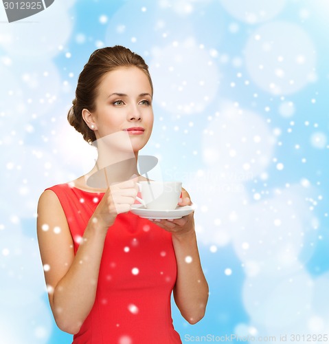 Image of smiling woman in red dress with cup of coffee