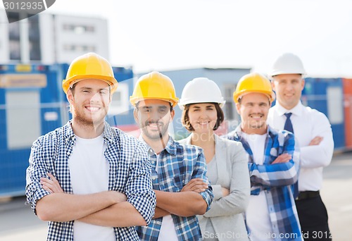 Image of group of smiling builders in hardhats outdoors