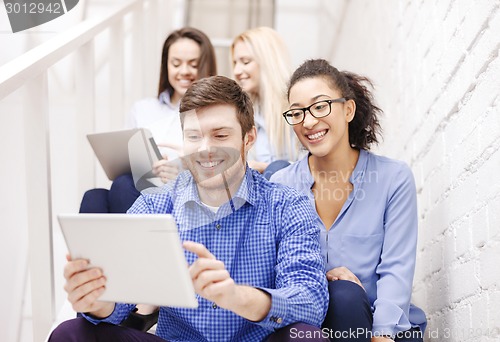 Image of team with tablet pc computer sitting on staircase