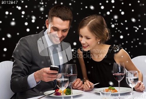 Image of smiling couple with smartphone at restaurant